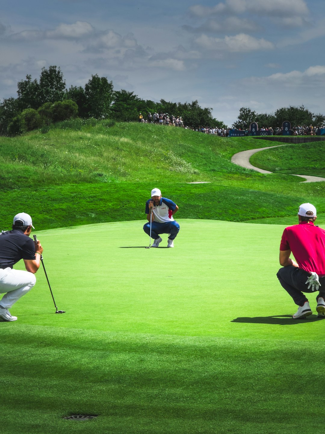 Scottie Sheffler, Tom Kim and Thomas Detry reading a putt on the 8th tee of the golf Olympics